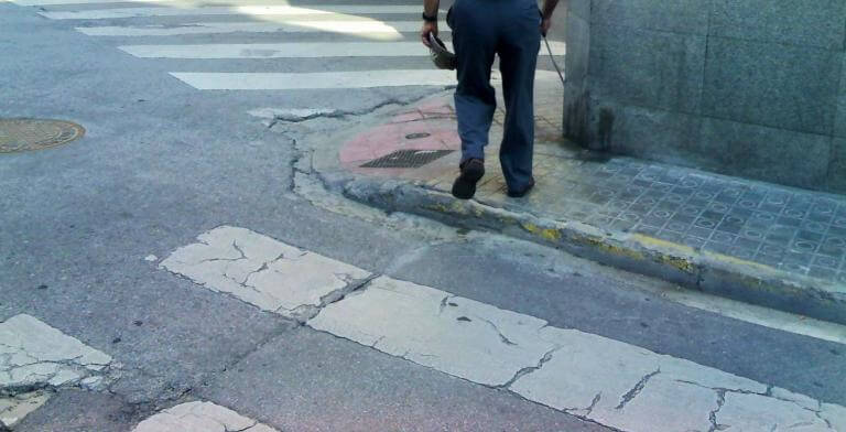 imagen de un señor (sólo se ven las piernas) cruzando un paso de cebra donde la acera no está adaptada