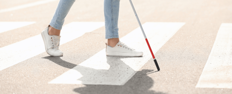 Dona amb discapacitat visual creuant  el pas de vianants.