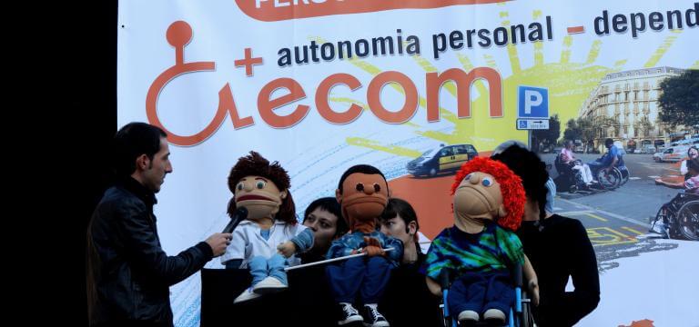 Escenari on estan s'està representant l'espectacle de titelles d'ECOM, davant una pancarta reivindicativa on s'identifica que és el Dia Internacional de la Discapacitat